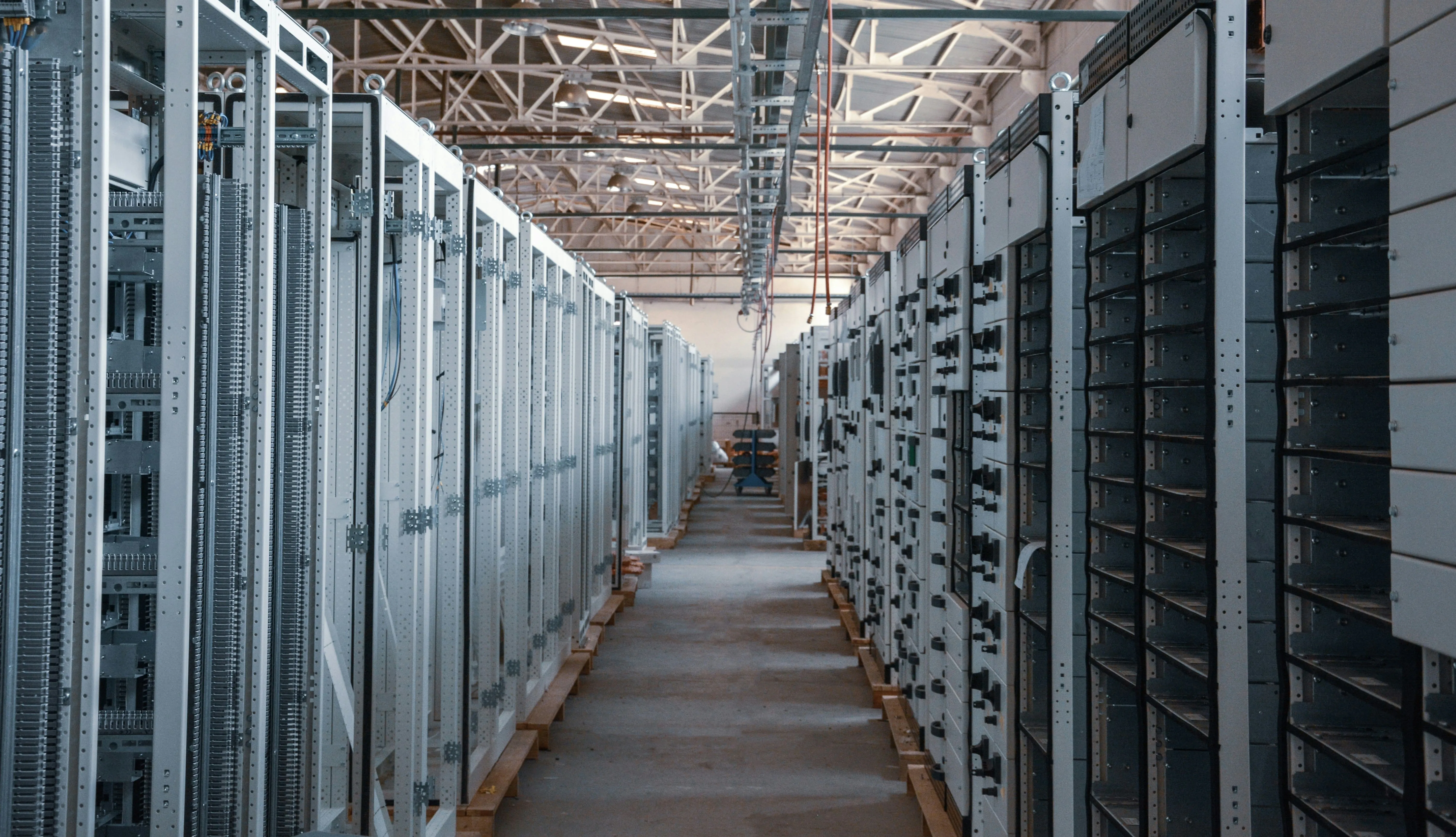 Long aisle of industrial electrical switchgear cabinets inside a clean, well-lit facility